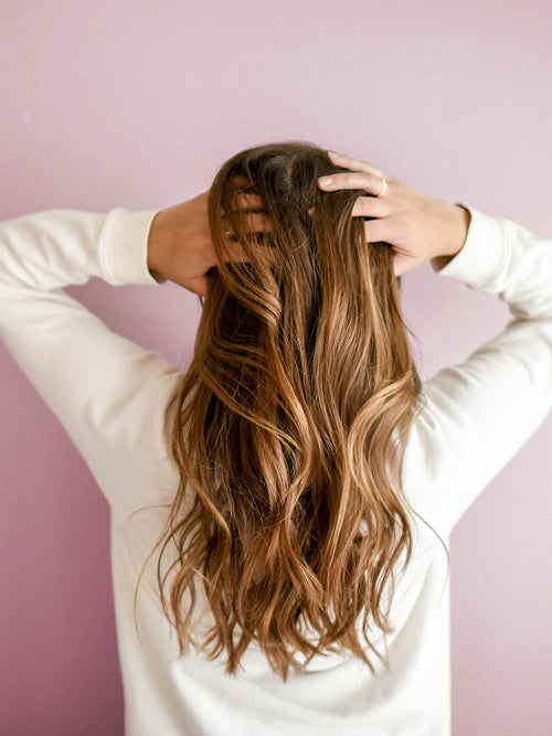 Femme aux cheveux longs de dos qui se tient sa tête