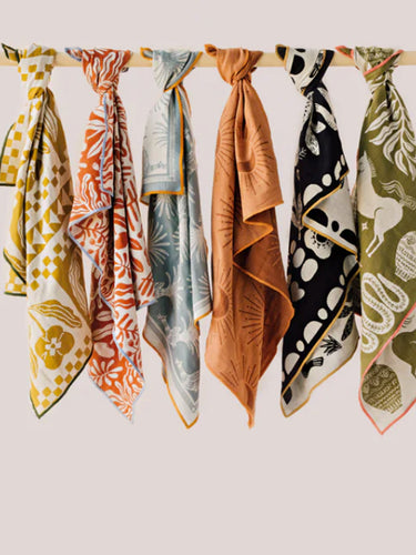 Différents linges à vaisselle suspendus sur une tige en bois.